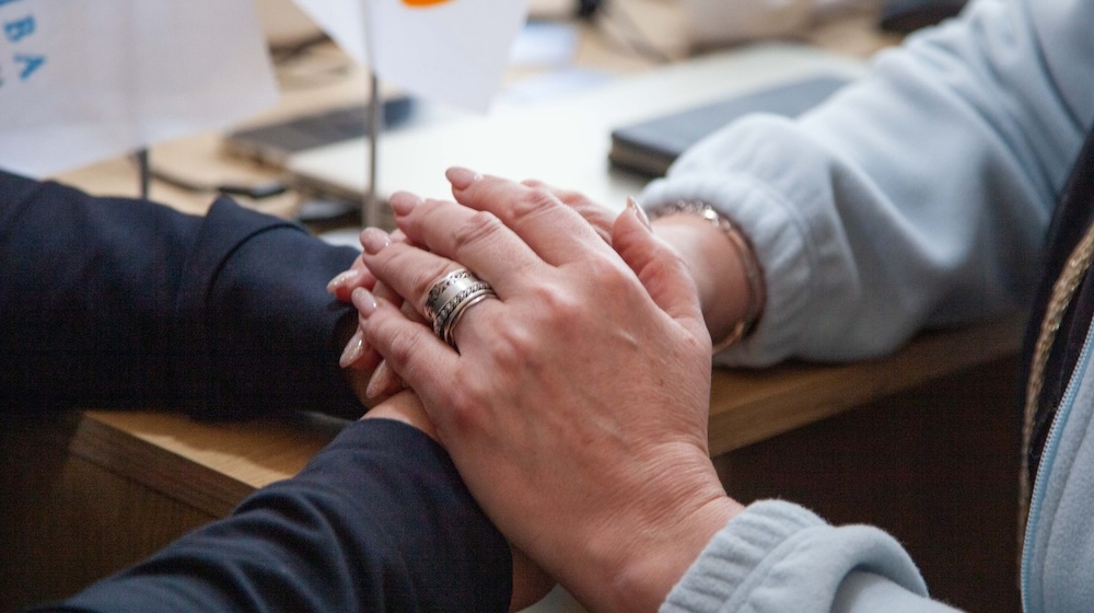 Des mains posées sur d'autres mains dans un signe de réconfort