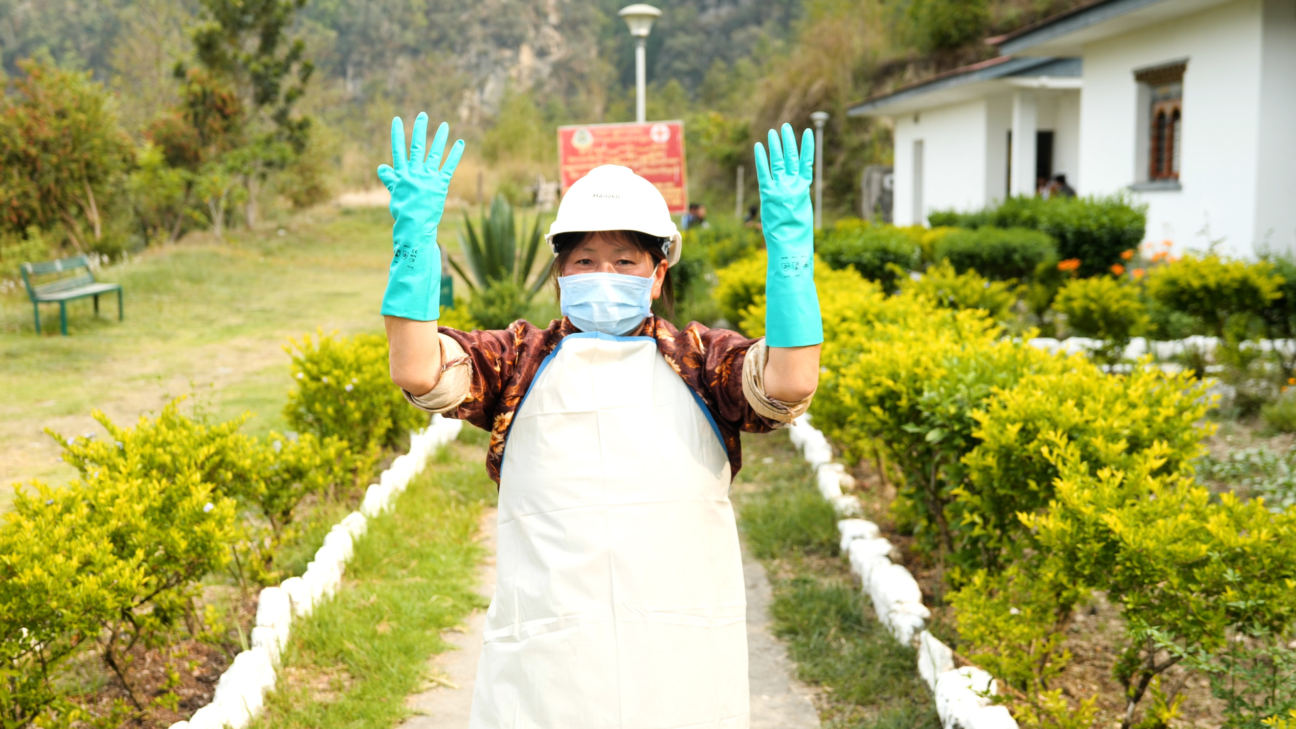Lien vers l'article sur le site du PNUD une femme portsnt des gants, un masque, un casque et un tablier de protection