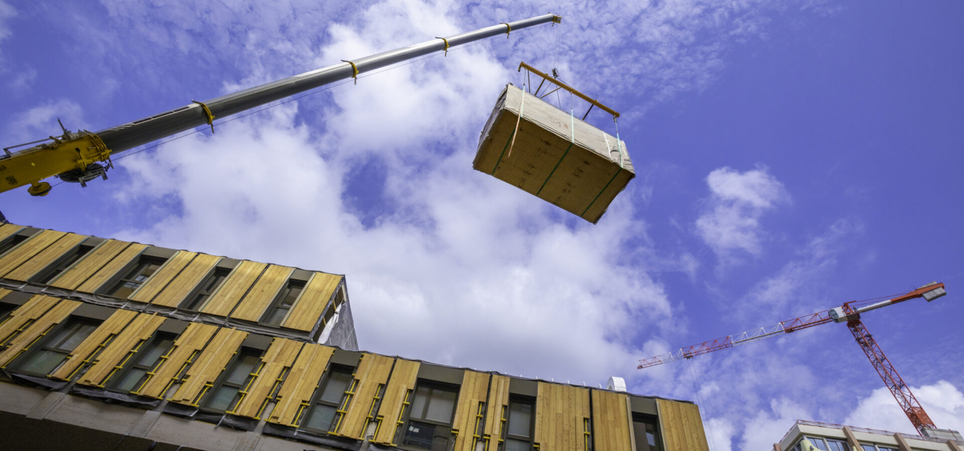 Une grue transportant une caisse en bois.