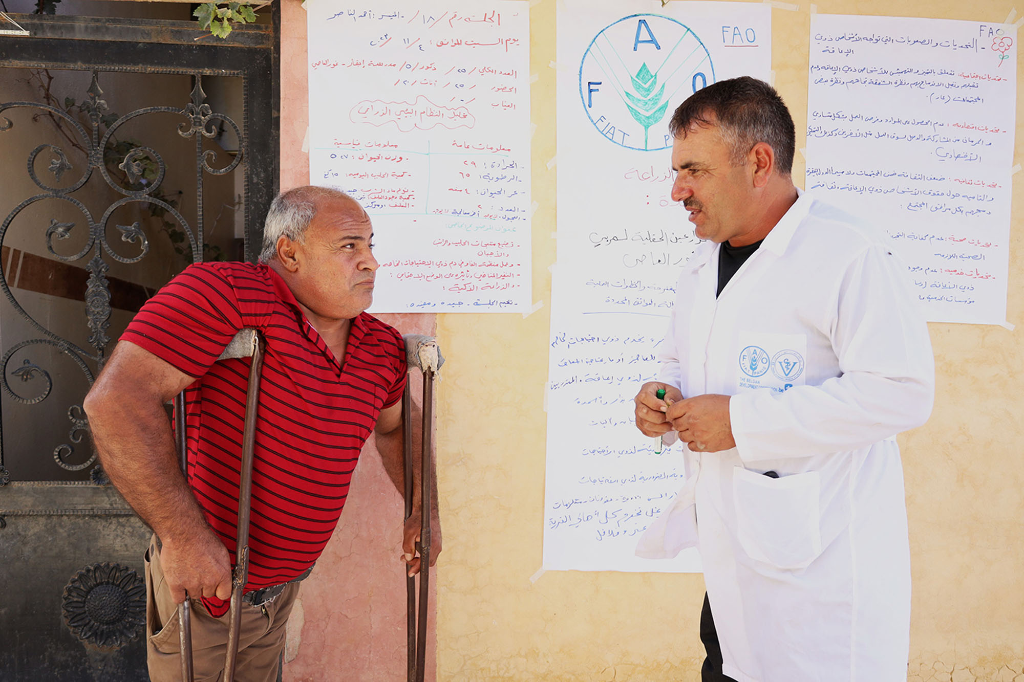 A man on crutches talks to an FAO official.