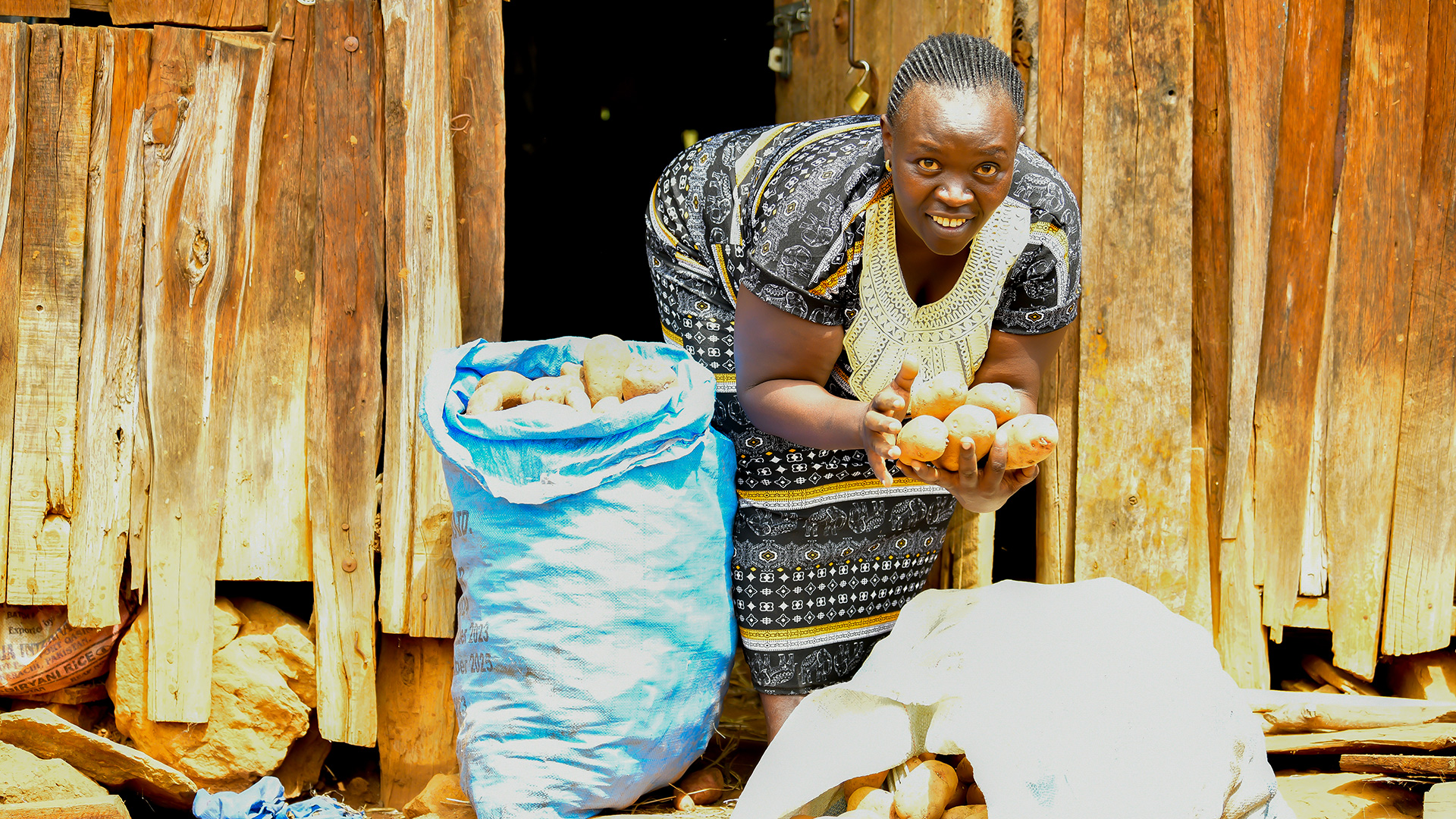 Une agricultrice africaine tient entre ses mains des pommes de terre